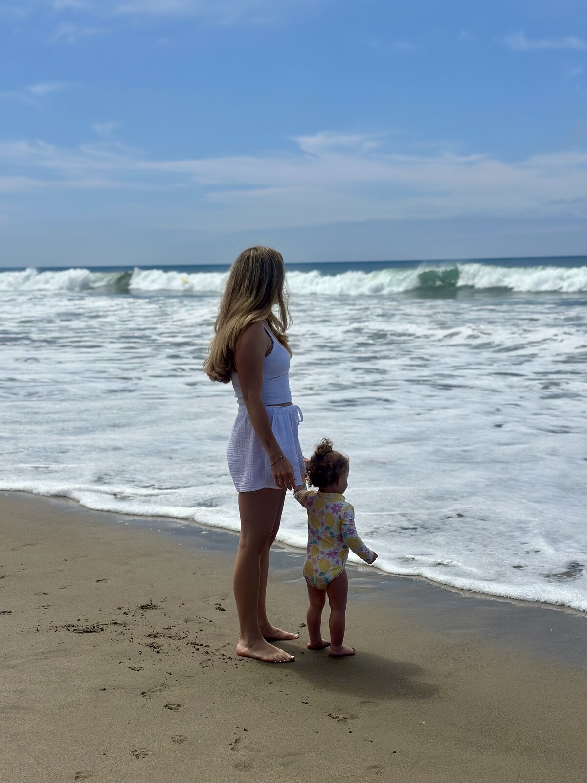 Kailey Webber walking on the beach, holding hands with her young daughter Presley